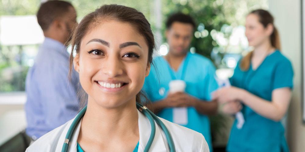 Woman med student smiling in front of other med students talking
